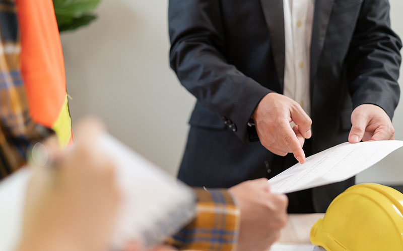 Mies osoittaa paperille kirjattua korjausvaatimusta